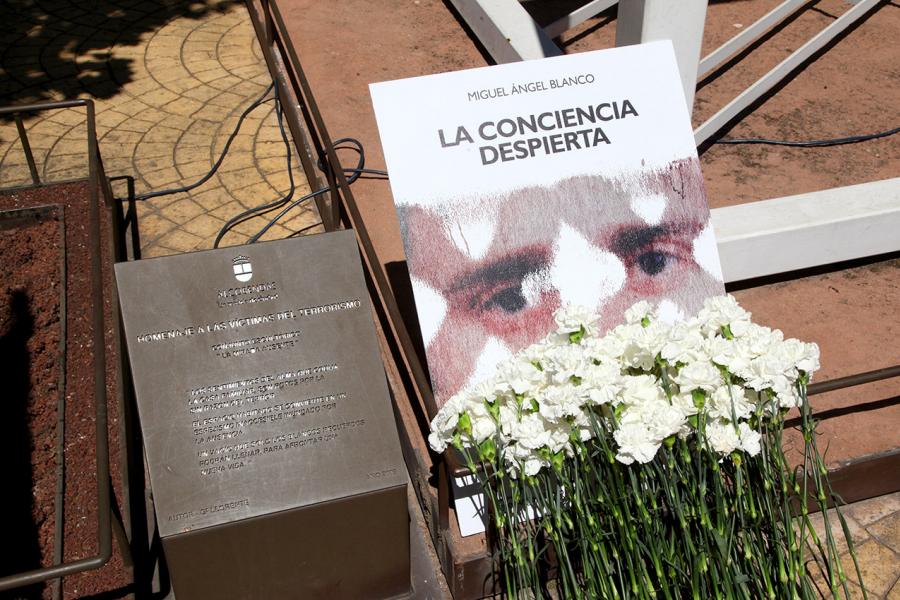 Homenaje a Miguel Ángel Blanco en el Parque Víctimas del Terrorismo - Placa conmemorativa,  el retrato y las flores junto al monumento.