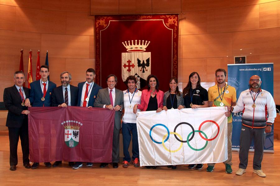 Homenajeados con autoridades posando con las banderas olímpica y de Alcobendas