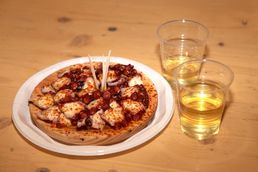 Semana Cultural Xuntanza de Galegos - Inauguración de la Romeria del Pulpo y el Mejillón - Imagen de plato de pulpo a la gallega y vino blanco.