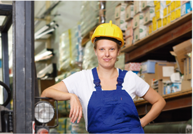 Imagen 3.png Mujer con mono de trabajo y casco en lo que parece un almacén