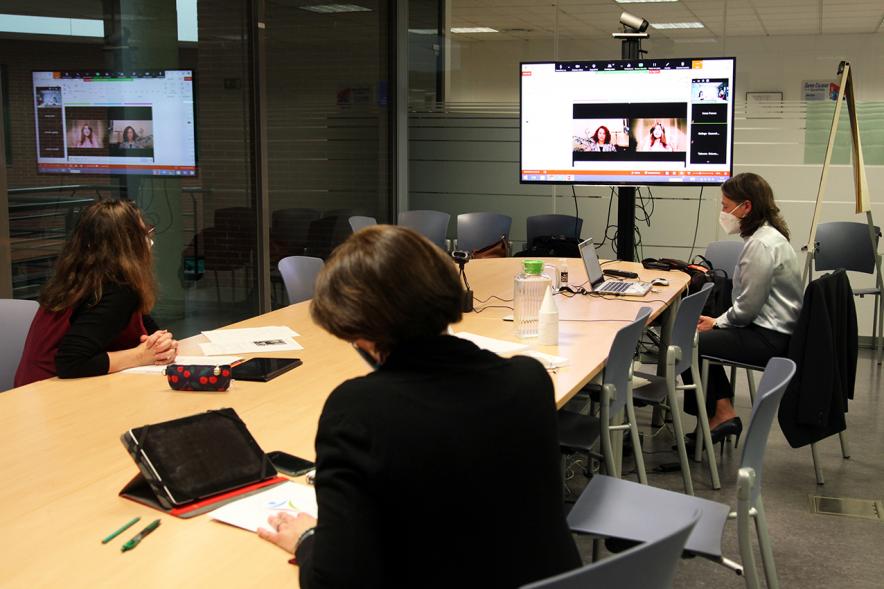 II Jornadas de Mediación Ciudad de Alcobendas -  Panorámica de una sala de reuniones con tres participantes, con mascarillas y la pantalla con una conferencia on line.