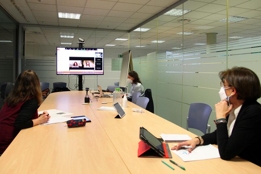 II Jornadas de Mediación Ciudad de Alcobendas - Panorámica de una sala de reuniones con tres participantes, con mascarillas y la pantalla con una conferencia on line.