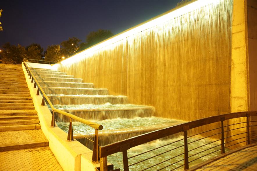 Campaña Mundial de sensibilización sobre el cáncer infantil "Enciende el oro/Enciende la esperanza". Iluminación cascada del Parque Valdelasfuentes -  Imagen parcial de la cascada y las escaleras iluminadas con luces doradas.