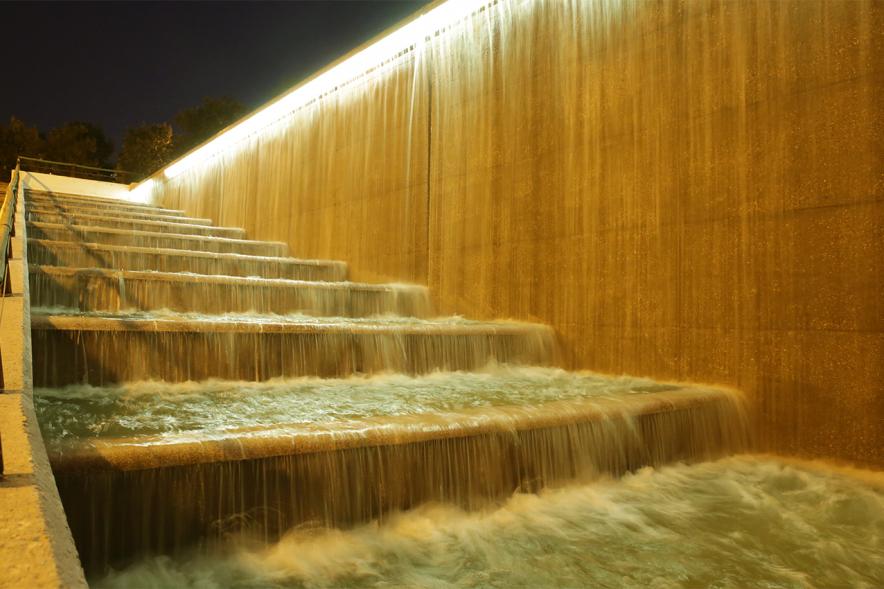 Campaña Mundial de sensibilización sobre el cáncer infantil "Enciende el oro/Enciende la esperanza". Iluminación cascada del Parque Valdelasfuentes -  Imagen parcial de la cascada iluminada con luces doradas.