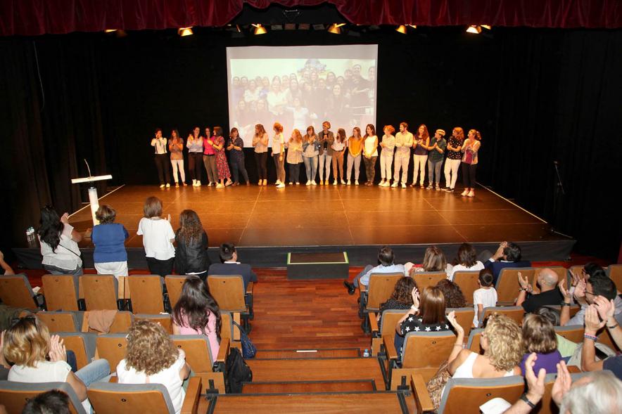 Presentación Curso Escolar 2019-20 APAMA - Panorámica del teatro con los  asistentes de pie  y  el saludo desde el escenario.