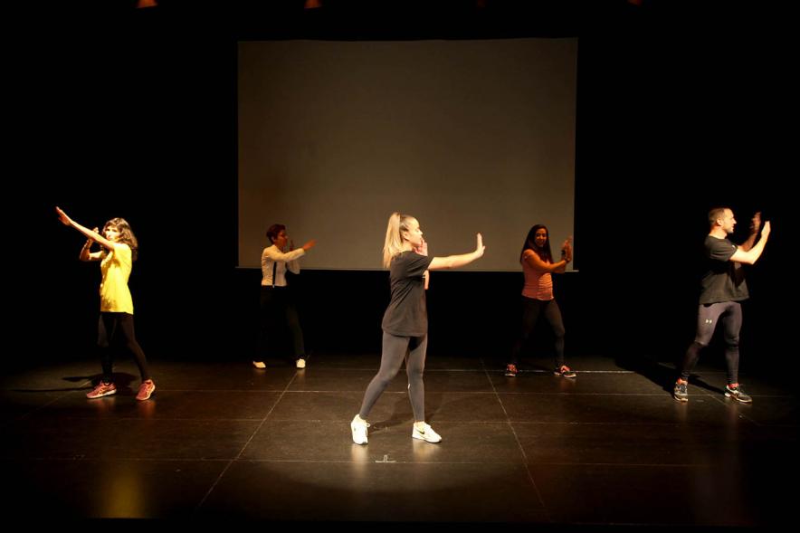 Presentación Curso Escolar 2019-20 APAMA - Imagen de seis jóvenes en el escenario moviéndose despacio.