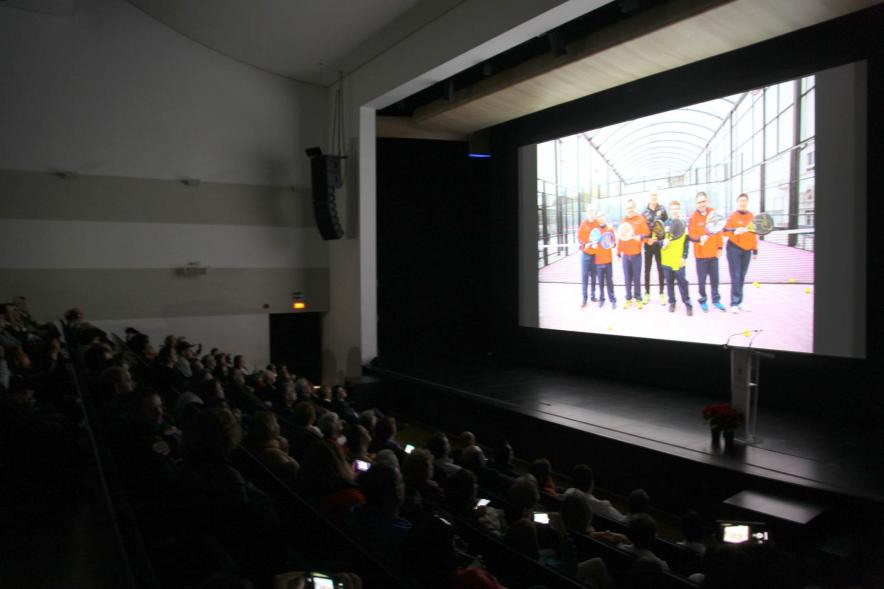 Presentación Calendario APAMA 2020 - Imagen del escenario a oscuras donde están viendo imágenes en una pantalla.