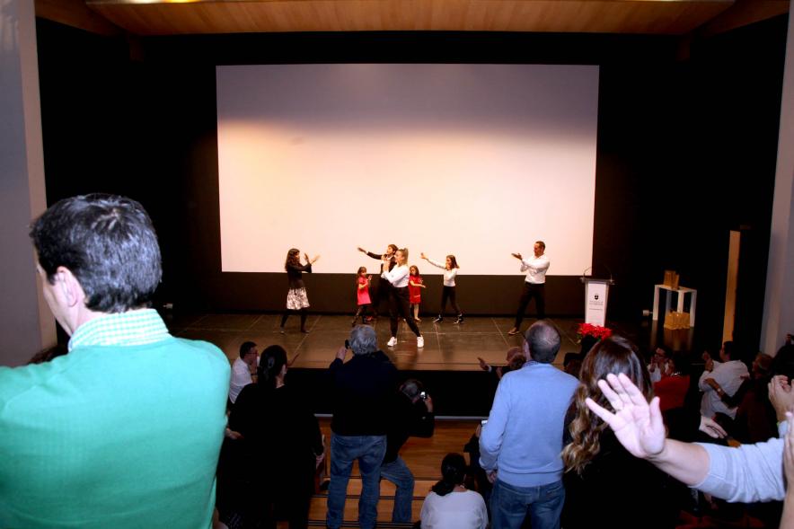 Presentación Calendario APAMA 2020 - Imagen lejana de personas en el escenario haciendo un baile que el público asistente que también lo trata de hacer.
