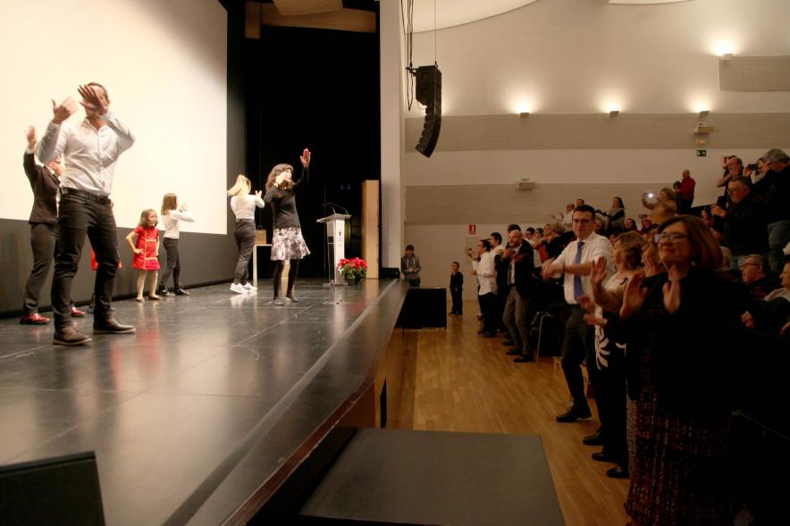 Presentación Calendario APAMA 2020 - Imagen de personas en el escenario haciendo un baile que el público asistente que también lo trata de hacer.