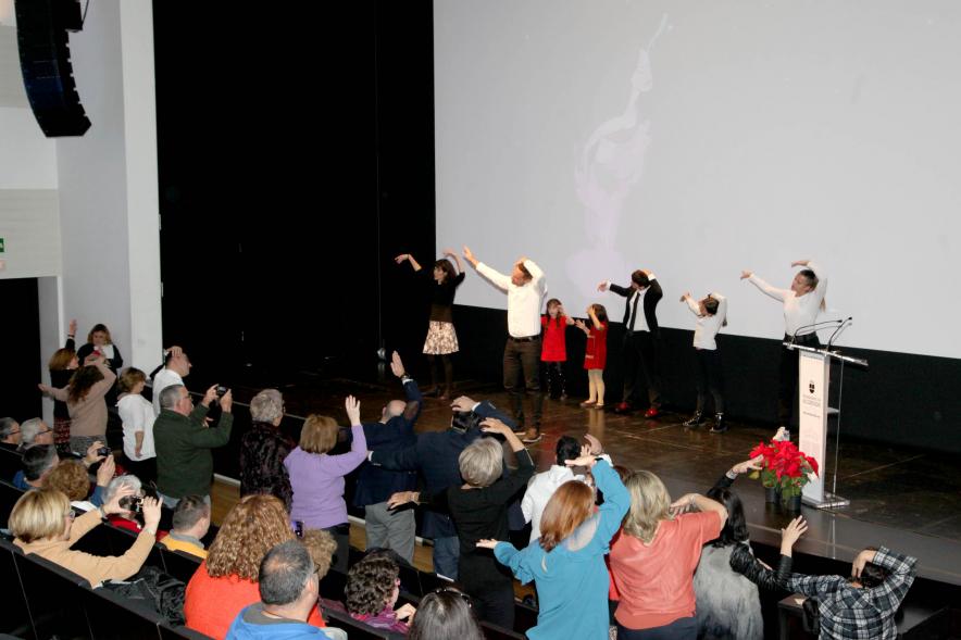Presentación Calendario APAMA 2020 - Imagen de personas en el escenario haciendo un baile que el público asistente que también lo trata de hacer.