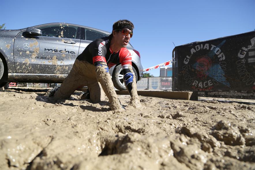 Gladiator Race - Un participante reptando sobre el barro.