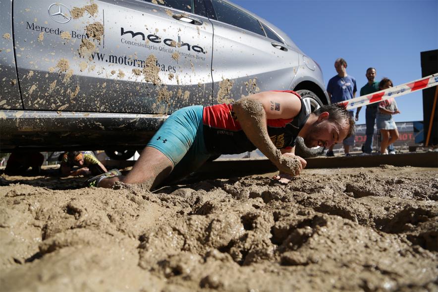 Gladiator Race - Un participante reptando sobre el barro.