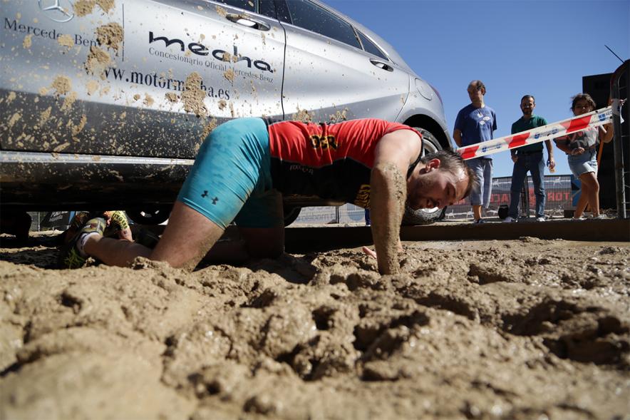 Gladiator Race - Un participante reptando sobre el barro.
