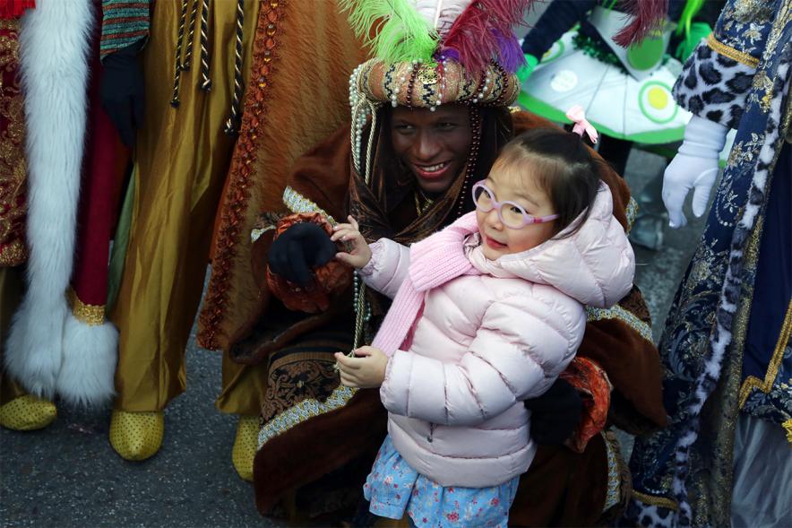 Cabalgata de Reyes 2019 - Imagen del Rey Baltasar posando junto a una niña.