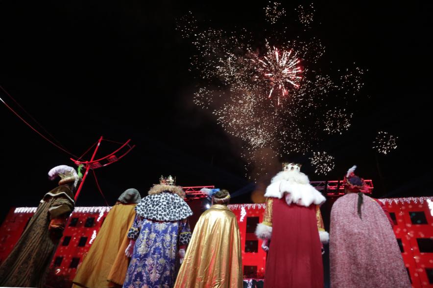 Cabalgata de Reyes 2019 - Imagen de los tres Reyes Magos en el escenario acompañados de sus respectivos pajes mirando hacia el cielo donde podemos ver los fuegos artificiales.