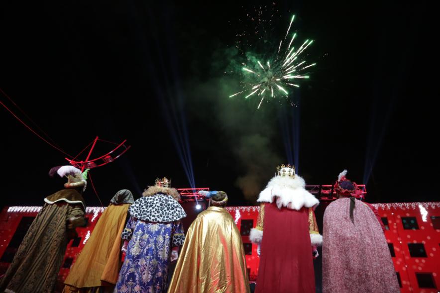 Cabalgata de Reyes 2019 - Imagen de los tres Reyes Magos en el escenario acompañados de sus respectivos pajes mirando hacia el cielo donde podemos ver los fuegos artificiales.