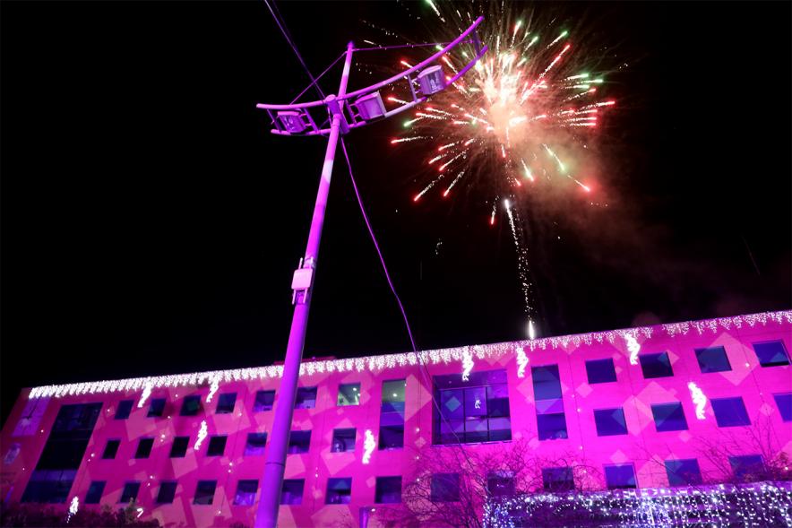 Cabalgata de Reyes 2019 - Imagen de la fachada del Ayuntamiento iluminada en en rosa y en el cielo fuegos artificiales.