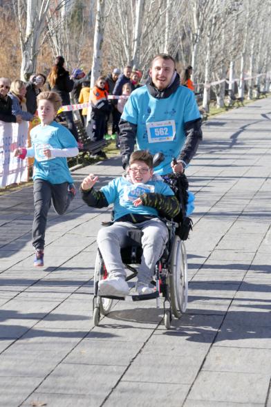 Carrera Fundación Adifun - Imagen de un corredor  empujando  a un niño en silla de ruedas.