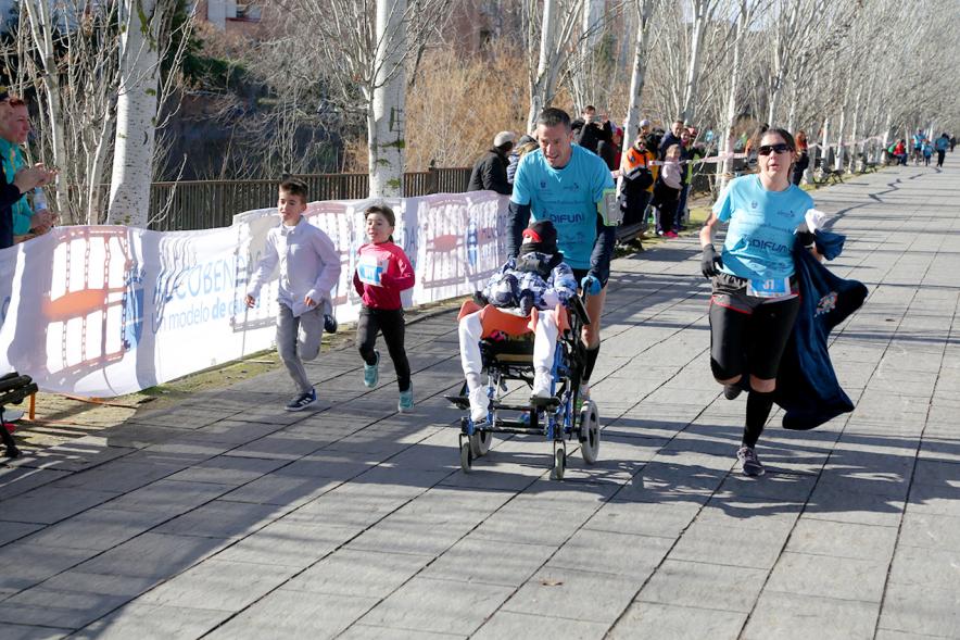Carrera Fundación Adifun - Imagen de un  corredor empujando a un niño en silla de ruedas.
