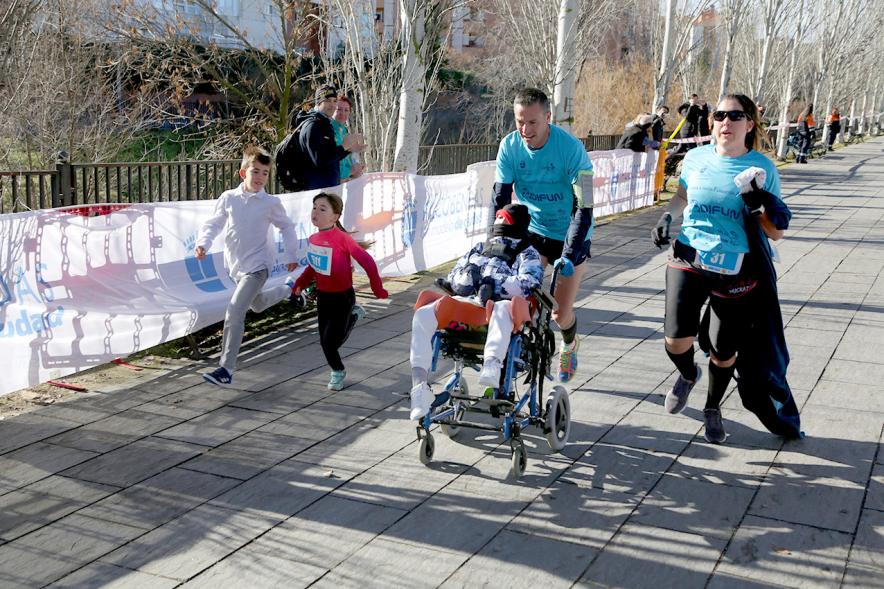 Carrera Fundación Adifun - Imagen de un  corredor empujando a un niño en silla de ruedas.