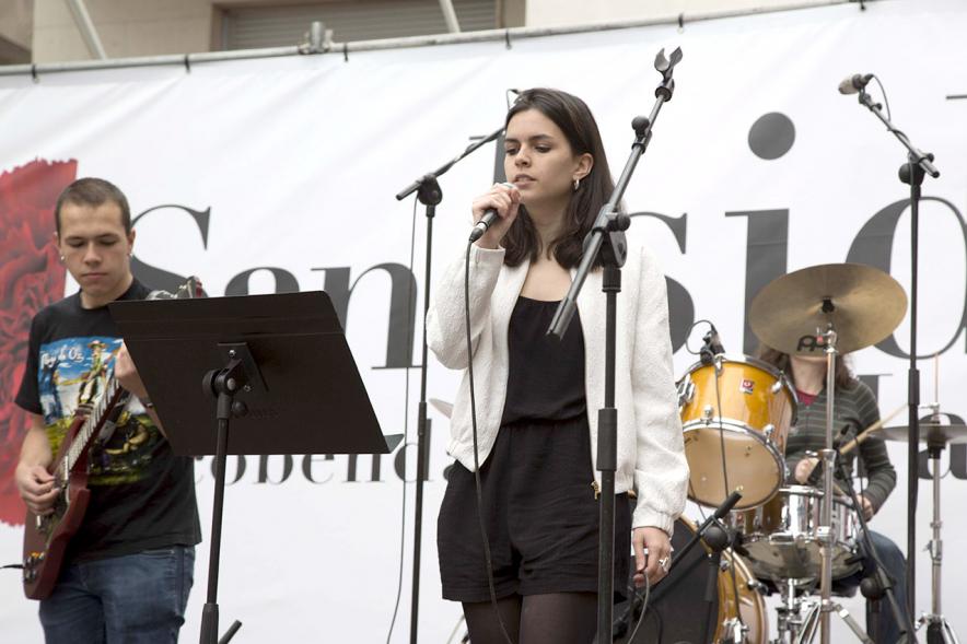 Cantante al micrófono con miembros de la banda al fondo