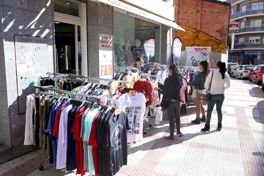 Visita Tiendas Alcostock 2019 - Imagen de varias personas mirando los percheros que hay montado en el exterior de una de las tiendas participantes en la feria.