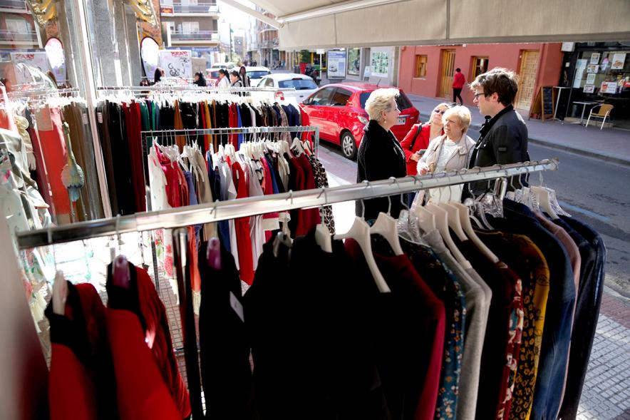 Visita Tiendas Alcostock 2019 - Imagen de varias personas mirando los percheros que hay montado en el exterior de una de las tiendas participantes en la feria.