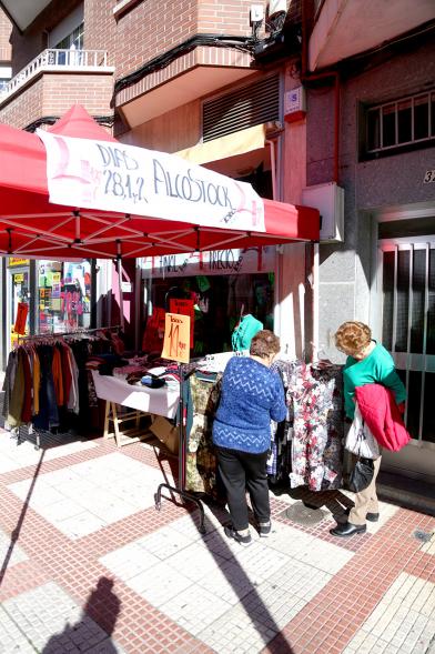 Visita Tiendas Alcostock 2019 - Imagen de varias personas mirando el mostrador que hay montado en el exterior de una de las tiendas participantes en la feria.