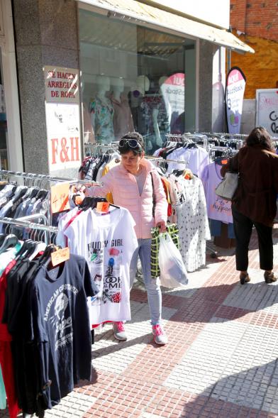 Visita Tiendas Alcostock 2019 - Imagen de una persona mirando los percheros que hay montado en el exterior de una de las tiendas participantes en la feria.