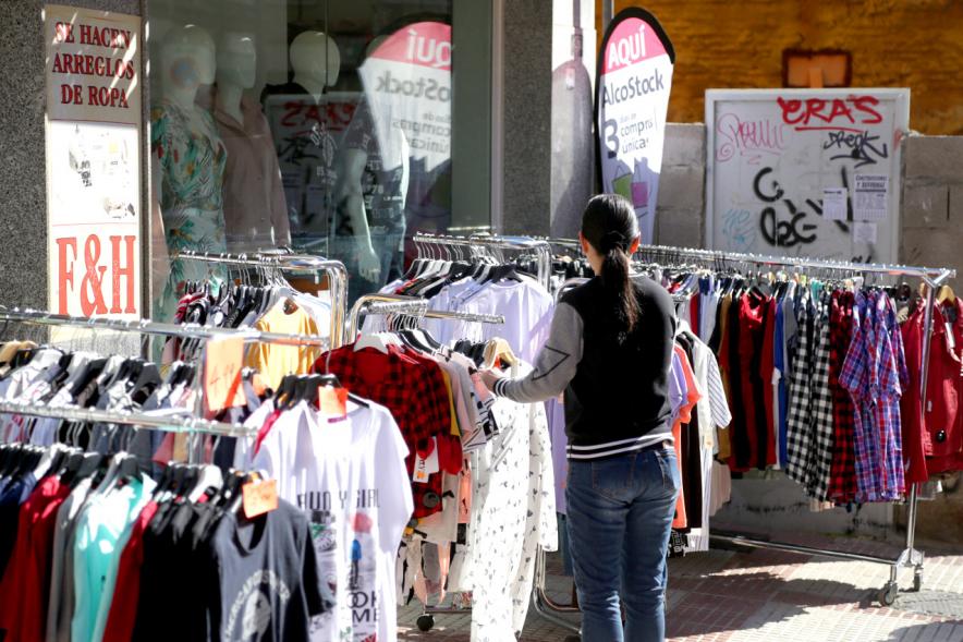 Visita Tiendas Alcostock 2019 - Imagen de una persona mirando los percheros que hay montado en el exterior de una de las tiendas participantes en la feria.