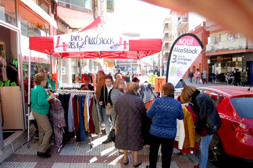Visita Tiendas Alcostock 2019 - Imagen de varias personas mirando los percheros que hay montado en el exterior de una de las tiendas participantes en la feria.