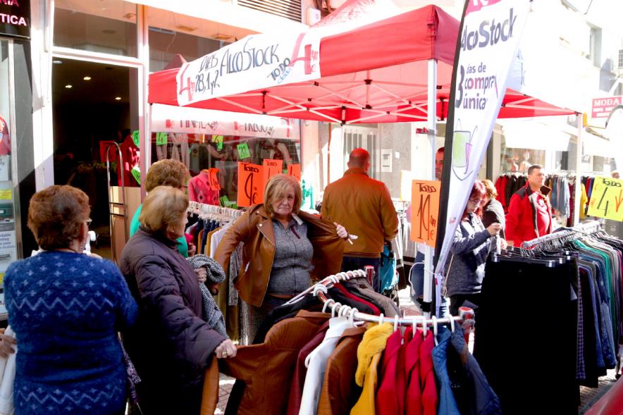 Visita Tiendas Alcostock 2019 -  Imagen de varias personas mirando los percheros que hay montado en el exterior de una de las tiendas participantes en la feria.