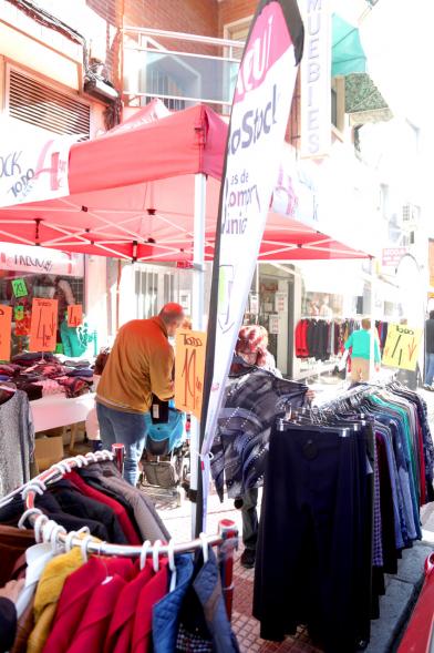 Visita Tiendas Alcostock 2019 - Imagen de varias personas mirando los percheros que hay montado en el exterior de una de las tiendas participantes en la feria.