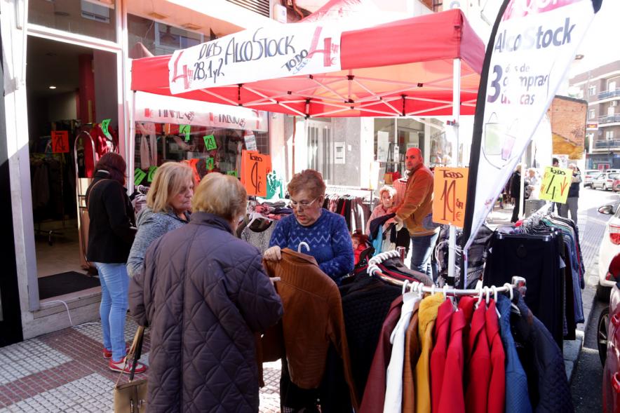 Visita Tiendas Alcostock 2019 - Imagen de varias personas mirando los percheros que hay montado en el exterior de una de las tiendas participantes en la feria.