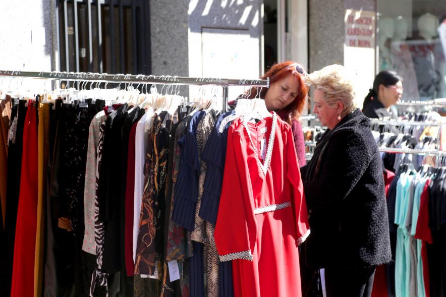 Visita Tiendas Alcostock 2019 - Imagen de varias personas mirando los percheros que hay montado en el exterior de una de las tiendas participantes en la feria.