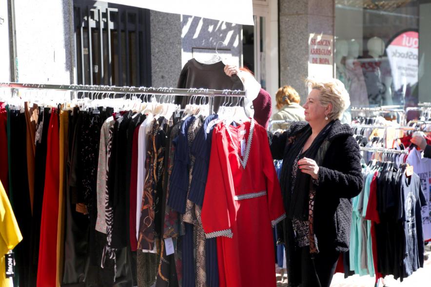 Visita Tiendas Alcostock 2019 - Imagen de varias personas mirando los percheros que hay montado en el exterior de una de las tiendas participantes en la feria.