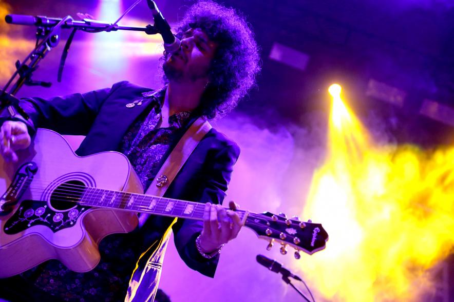 Cantante con guitarra bajo focos morados