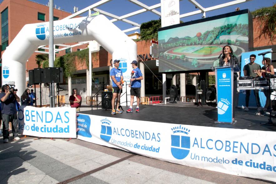 Carrera de la Antorcha Olímpica - Imagen de personas en el escenario y una de ellas dirigiéndose al público.