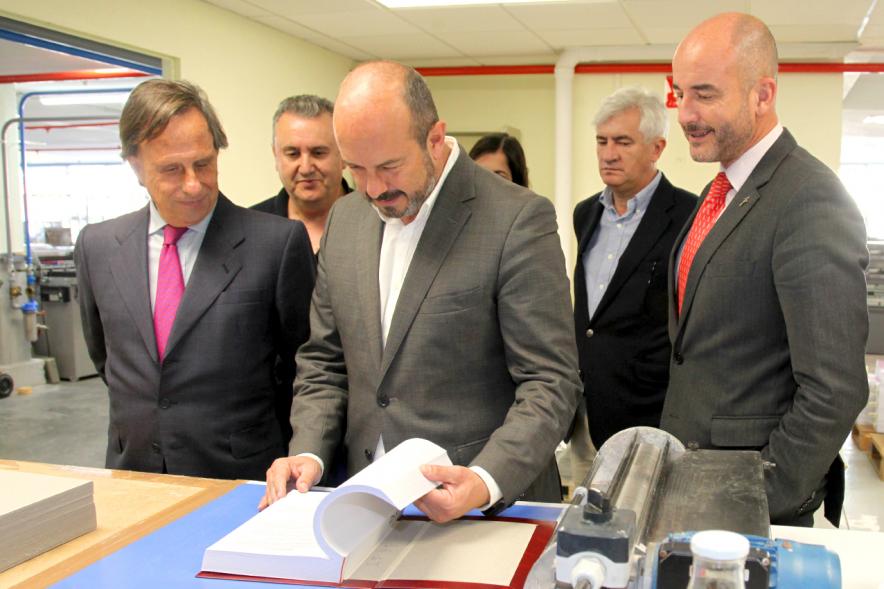 Visita Vicepresidente de la CAM a la Sede del BOCM - Imagen del Vicepresidente hojeando una prueba del BOCM junto al alcalde García de Vinuesa, varios concejales y un trabajador.