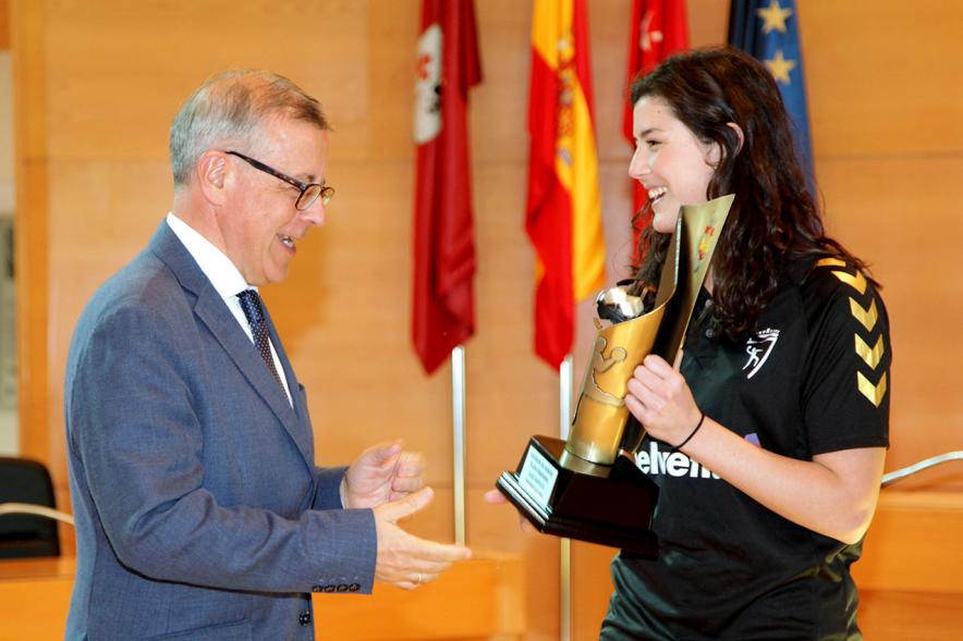 Recepción por los Ascensos del Equipo Femenino y Masculino de Balonmano - Imagen jugadora mostrando el trofeo ganado a una autoridad.