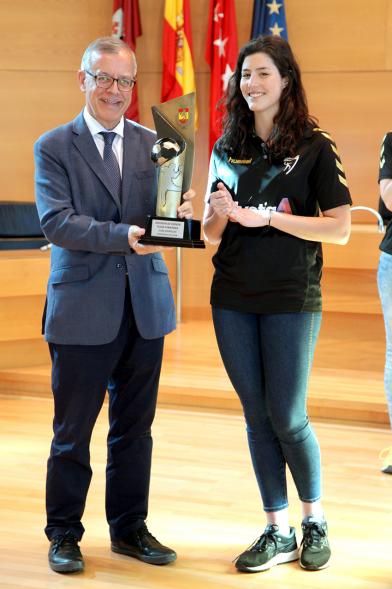 Recepción por los Ascensos del Equipo Femenino y Masculino de Balonmano - Imagen una jugadora mostrando el trofeo ganado a una autoridad.