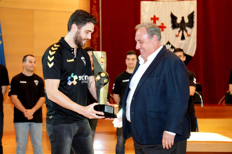 Recepción por los Ascensos del Equipo Femenino y Masculino de Balonmano - Imagen un jugador mostrando el trofeo ganado a una autoridad.