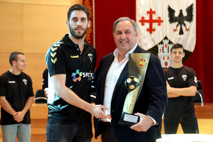 Recepción por los Ascensos del Equipo Femenino y Masculino de Balonmano - Imagen un jugador mostrando el trofeo ganado a una autoridad.