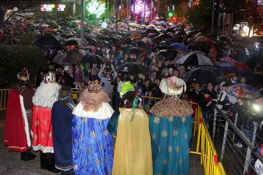 Cabalgata de Reyes 2018 - Imagen de los Reyes Magos de espalda con sus pajes saludando a la gente.