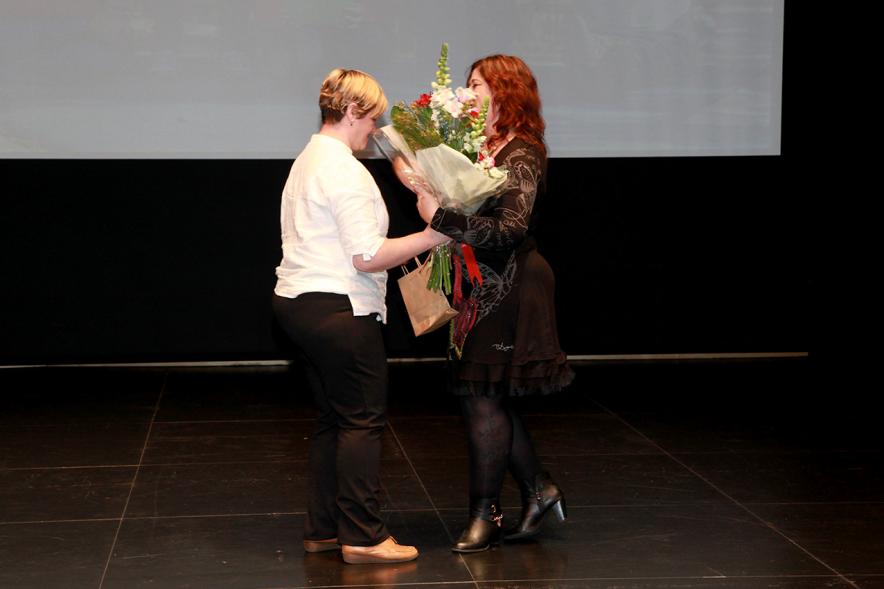 Presentación del Calendario de APAMA 2017 - Imagen de una mujer recibiendo un ramo de flores en el escenario.