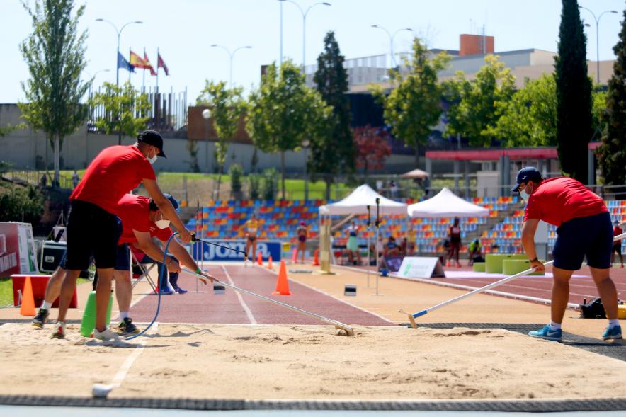 Campeonato de España de Atletismo - Salto de Altura y Triple Salto - Imagen de operarios alisando el foso de arena donde saltan las atletas.