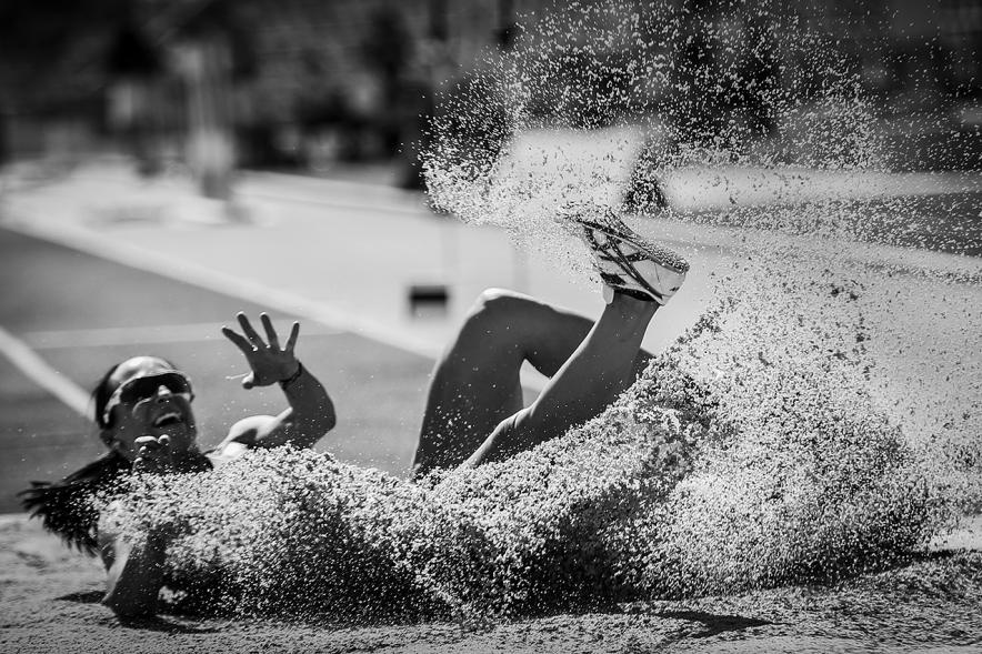 Campeonato de España de Atletismo - Salto de Altura y Triple Salto - Imagen en blanco y negro de una atleta realizando un triple salto en el momento de caer en la arena.