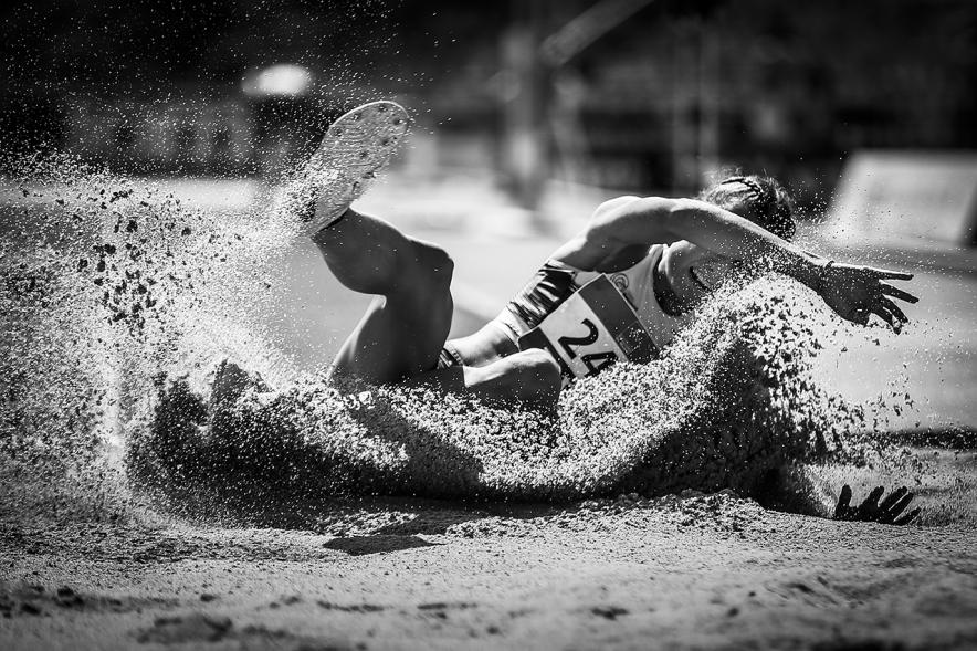 Campeonato de España de Atletismo - Salto de Altura y Triple Salto - Imagen en blanco y negro de una atleta realizando un triple salto en el momento de caer en la arena.