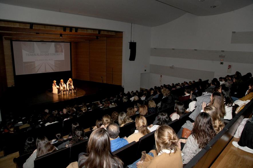 Charla "Tienen Algo que Decirte" - Panorámica del teatro completo con el escenario iluminado y con las ponentes.