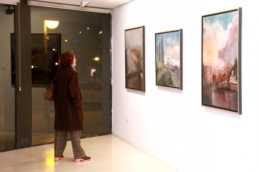 Inauguración Exposición de Charo Vaquerizo "Visiones Urbanas" - Imagen de persona mirando los cuadros de la exposición.